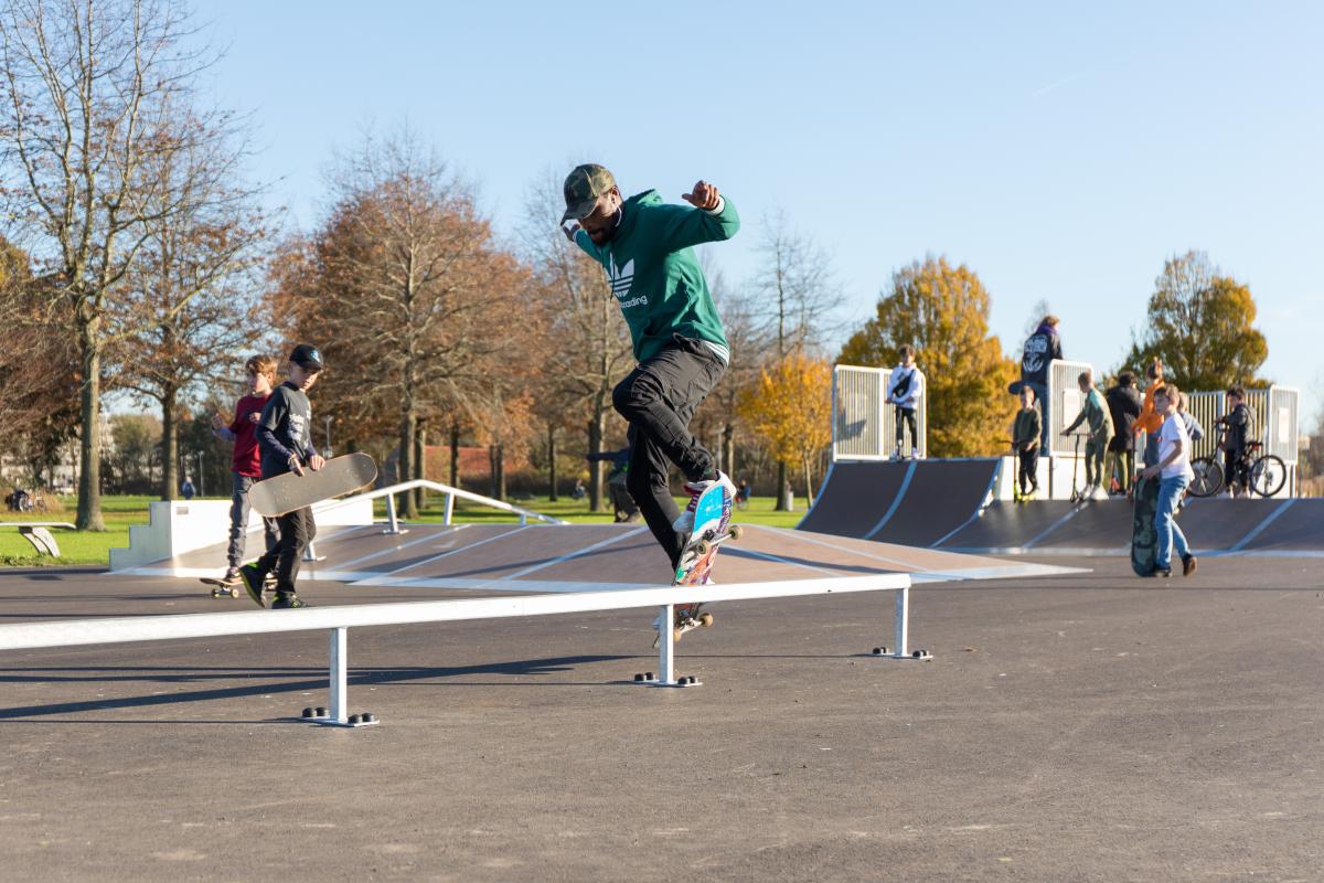 Een skateboarder doet een trucje in een skatepark.