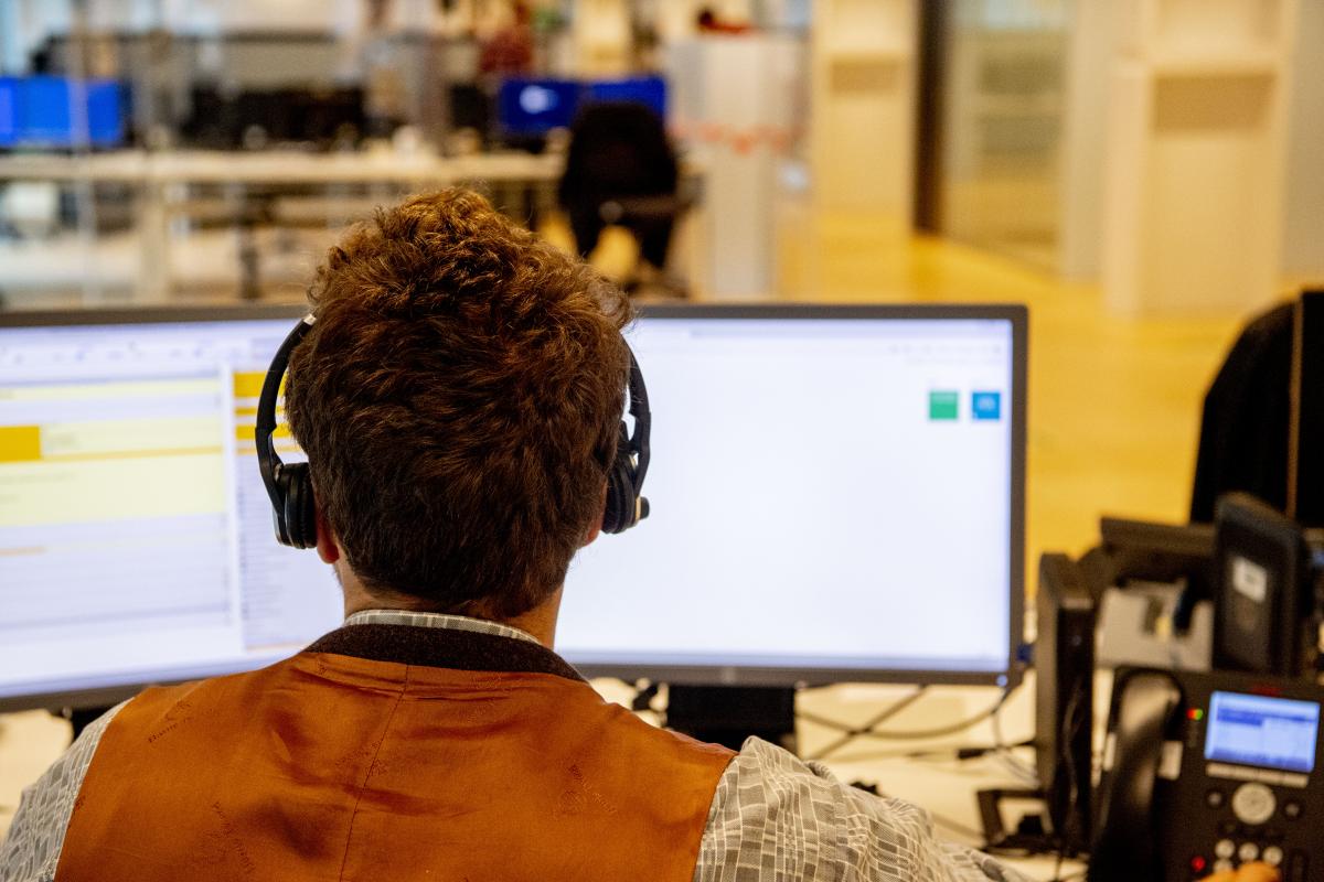 Man met headset achter een computerscherm